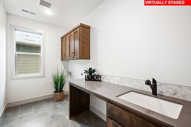 laundry area featuring light tile patterned floors, cabinets, and sink