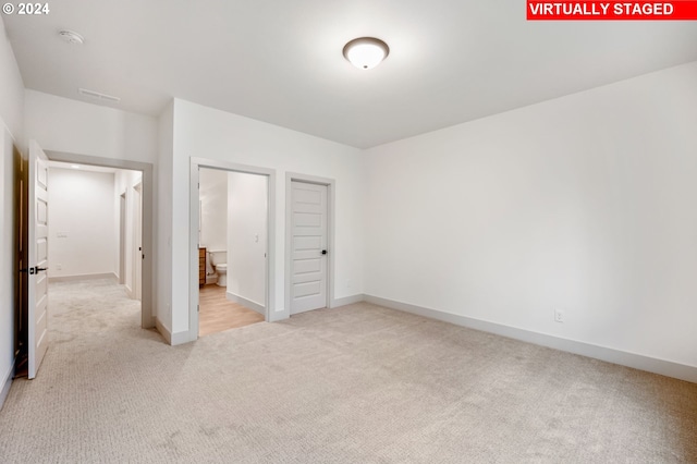 unfurnished bedroom with a closet and light colored carpet