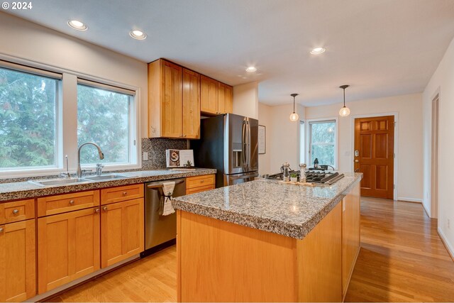 kitchen with dishwasher, sink, light wood-type flooring, and backsplash