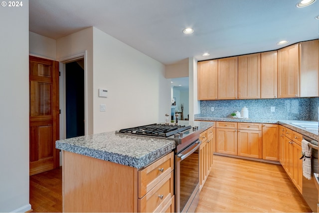 kitchen featuring a kitchen island, stainless steel appliances, decorative backsplash, light hardwood / wood-style flooring, and light brown cabinets