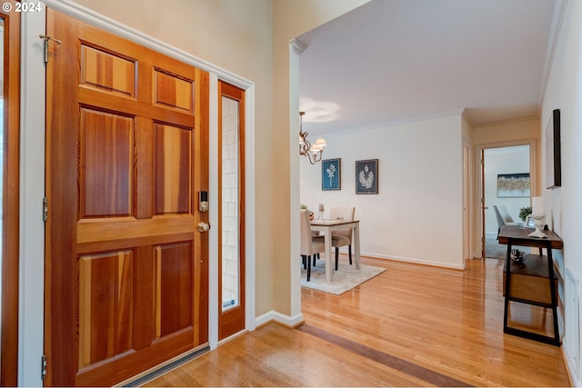 foyer entrance featuring ornamental molding, light hardwood / wood-style flooring, and a chandelier