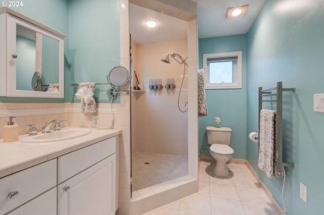 bathroom featuring vanity, toilet, tile patterned floors, and tiled shower