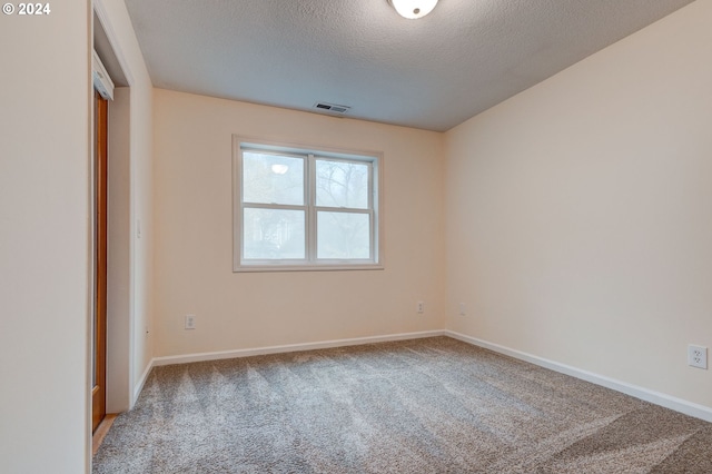 carpeted empty room with a textured ceiling