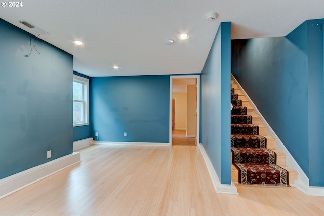 unfurnished living room featuring light hardwood / wood-style flooring and a textured ceiling