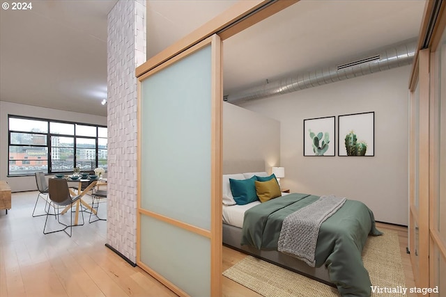 bedroom featuring wood-type flooring and brick wall