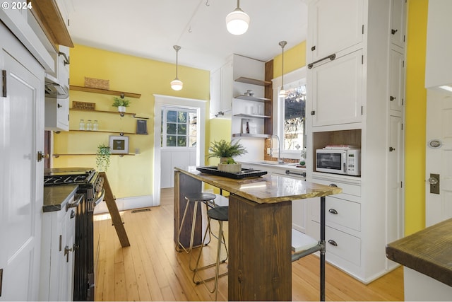 kitchen with white cabinets, gas range, plenty of natural light, and pendant lighting