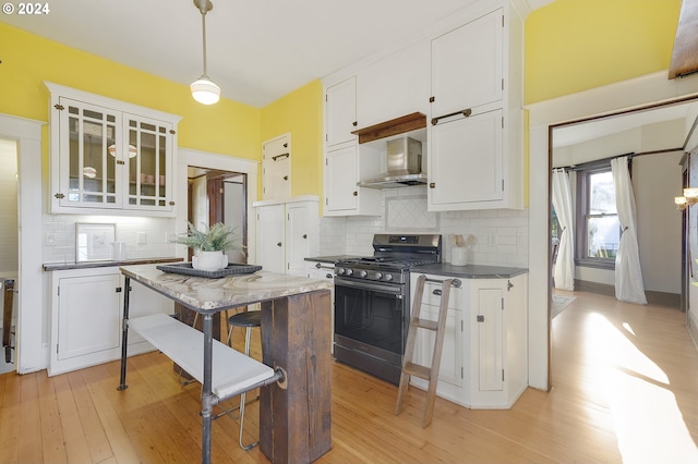 kitchen featuring gas range, light hardwood / wood-style floors, white cabinetry, and wall chimney exhaust hood