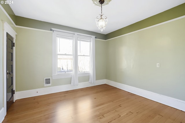 spare room featuring light hardwood / wood-style floors and an inviting chandelier