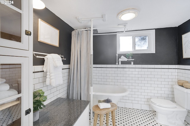 bathroom with tile patterned flooring, toilet, and tile walls