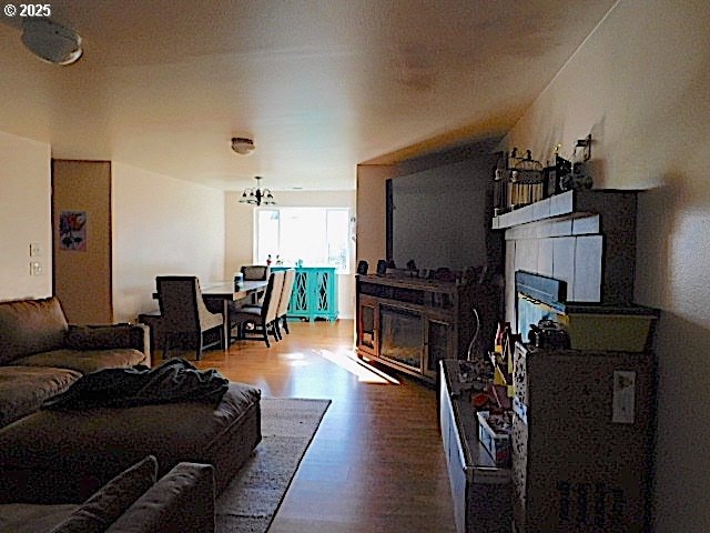 living room with a tile fireplace, wood-type flooring, and a notable chandelier