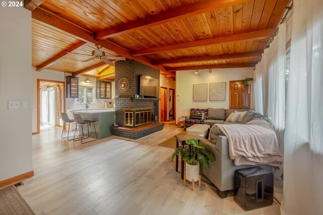 living room featuring light wood-type flooring, ceiling fan, beam ceiling, wooden ceiling, and a fireplace