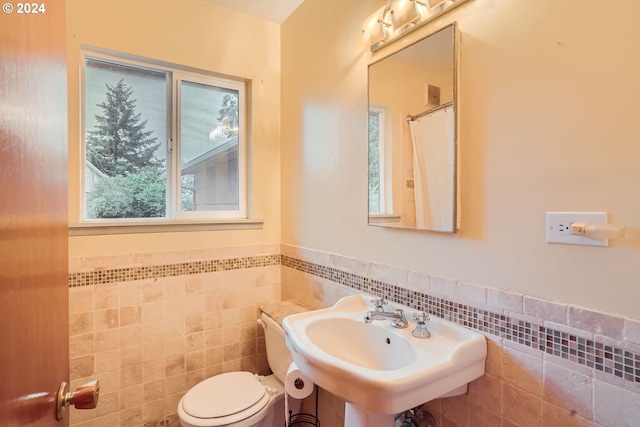 bathroom featuring sink, tile walls, and toilet