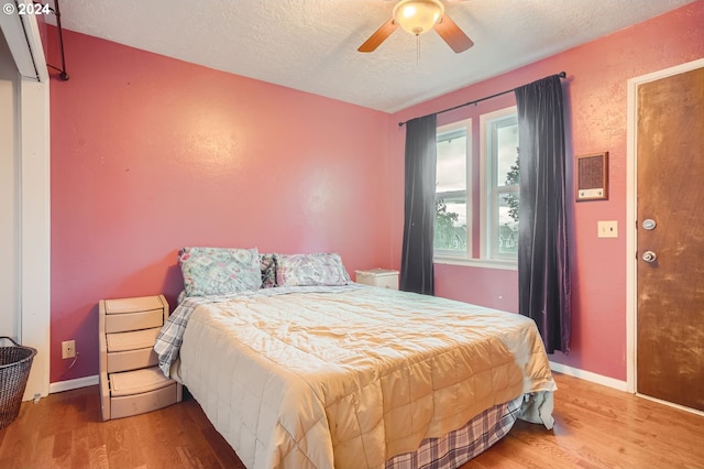 bedroom with ceiling fan, hardwood / wood-style floors, and a textured ceiling