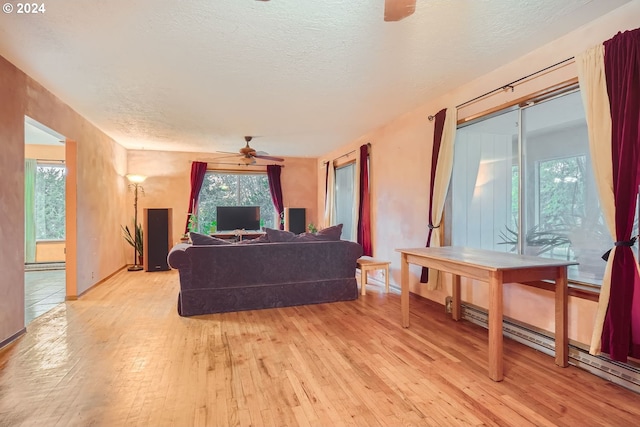 living room featuring light hardwood / wood-style flooring, ceiling fan, and a textured ceiling