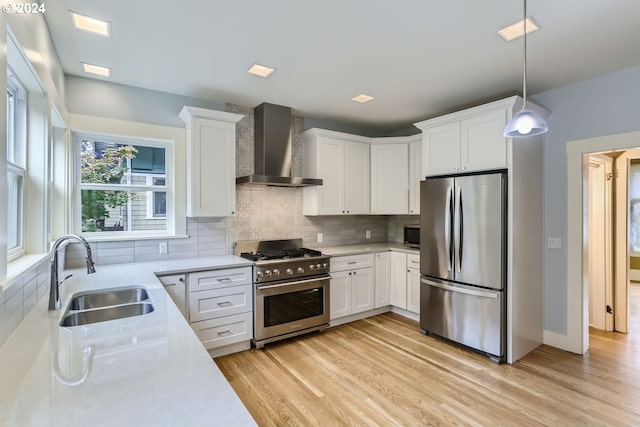 kitchen featuring sink, appliances with stainless steel finishes, white cabinetry, and wall chimney exhaust hood