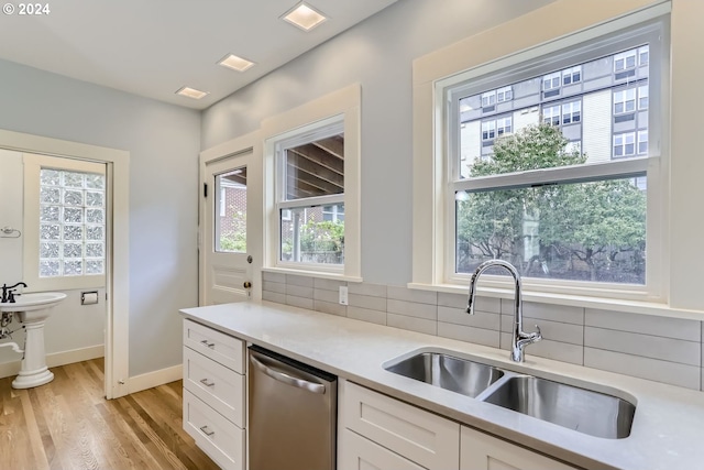 kitchen featuring light hardwood / wood-style flooring, sink, white cabinetry, dishwasher, and decorative backsplash