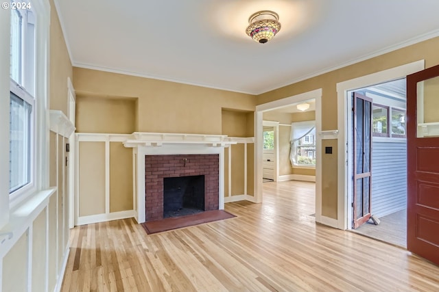 unfurnished living room featuring light hardwood / wood-style floors, ornamental molding, and a fireplace