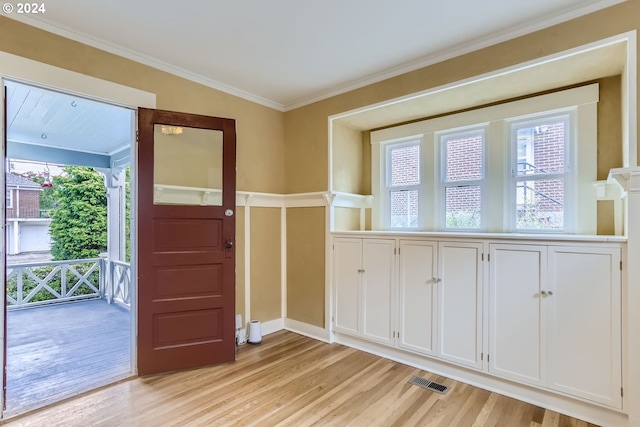 foyer with crown molding and light hardwood / wood-style flooring