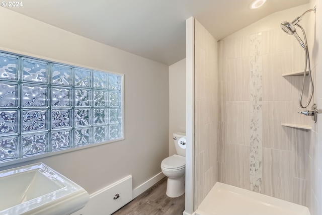 bathroom featuring toilet, hardwood / wood-style flooring, and tiled shower