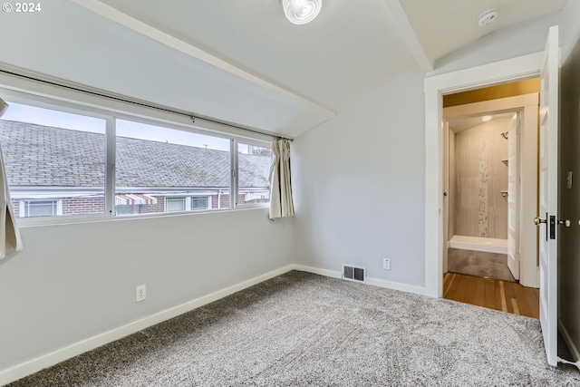 carpeted empty room with vaulted ceiling