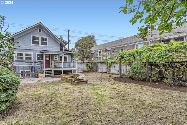 back of property with a deck and a lawn