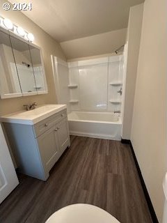 full bathroom with vanity, hardwood / wood-style floors, washtub / shower combination, and toilet