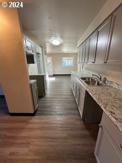 kitchen with light stone counters, sink, and dark hardwood / wood-style floors