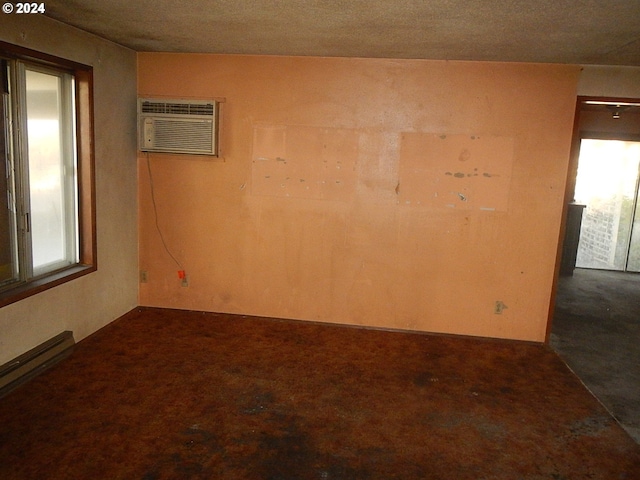 carpeted spare room with an AC wall unit, a textured ceiling, and baseboard heating