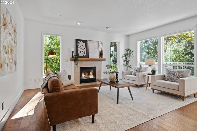 living room featuring light hardwood / wood-style floors, a tile fireplace, and a textured ceiling