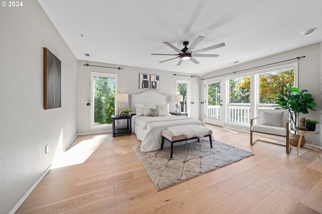 bedroom featuring ceiling fan, light hardwood / wood-style flooring, access to exterior, and multiple windows