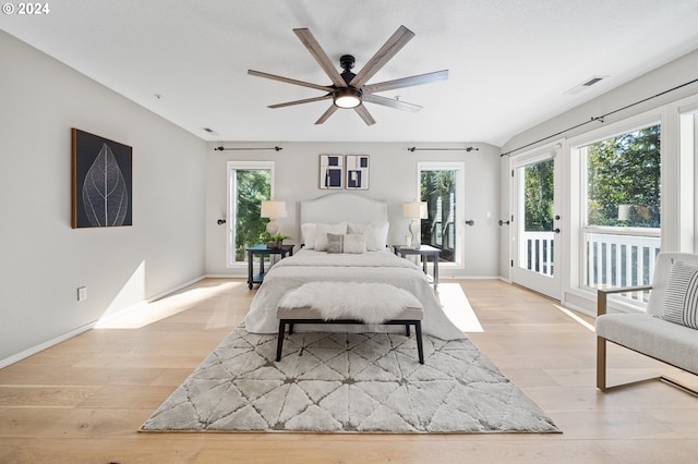 bedroom with multiple windows, light hardwood / wood-style flooring, ceiling fan, and access to exterior