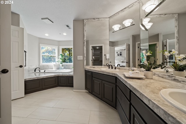 bathroom with vanity, a bathing tub, tile patterned flooring, and a textured ceiling