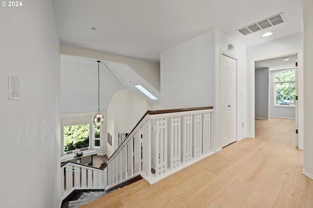 corridor with light hardwood / wood-style flooring and a chandelier