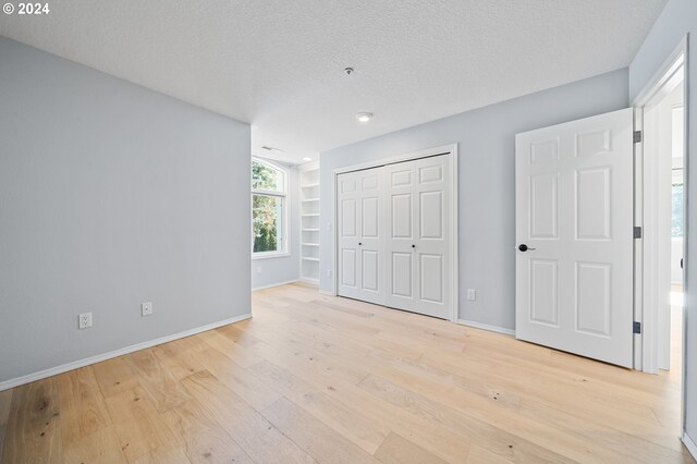 unfurnished bedroom featuring a textured ceiling, light hardwood / wood-style floors, and a closet