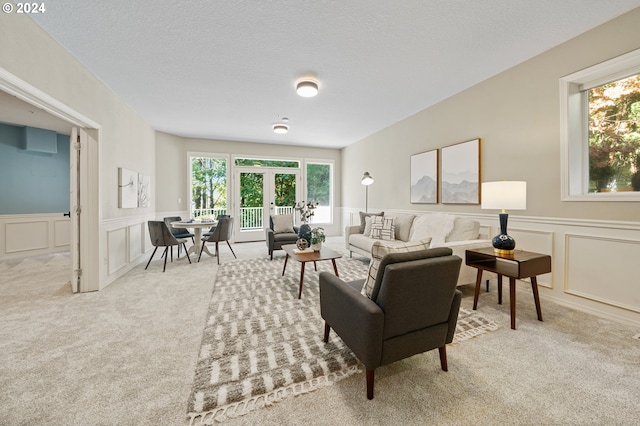 carpeted living room featuring french doors, a textured ceiling, and a healthy amount of sunlight