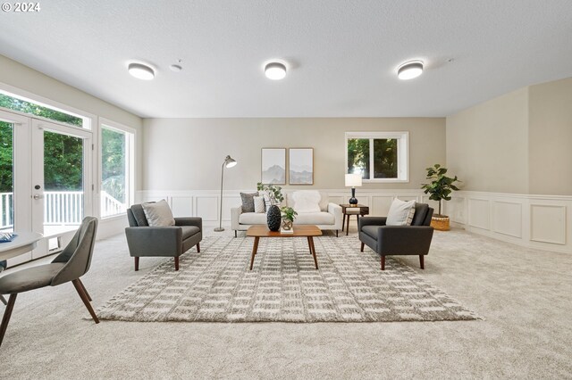 living room with a textured ceiling, carpet floors, and french doors