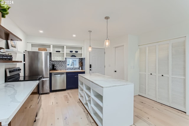 kitchen featuring a center island, light hardwood / wood-style floors, stainless steel appliances, pendant lighting, and blue cabinetry