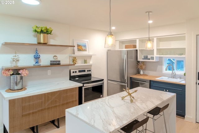 kitchen with appliances with stainless steel finishes, sink, hanging light fixtures, light stone countertops, and blue cabinetry