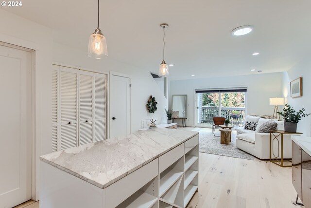 kitchen featuring stainless steel electric stove, white cabinets, hanging light fixtures, light hardwood / wood-style floors, and a center island