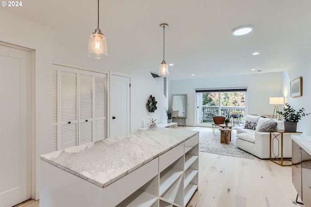 kitchen with a kitchen island, pendant lighting, white cabinets, and light hardwood / wood-style floors