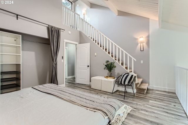 bedroom featuring high vaulted ceiling, a walk in closet, and light wood-type flooring