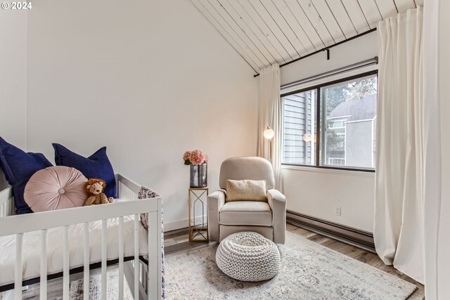 bedroom featuring hardwood / wood-style flooring, a crib, and a high ceiling