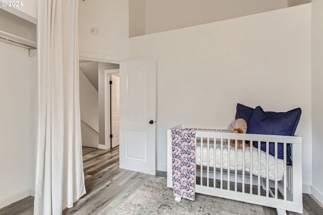 bedroom with hardwood / wood-style flooring and a crib