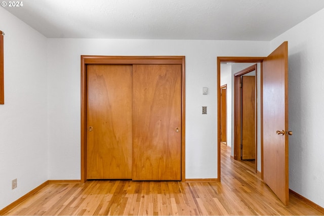 unfurnished bedroom with a closet and light wood-type flooring