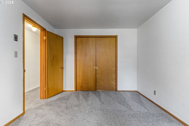 unfurnished bedroom featuring a closet and light carpet