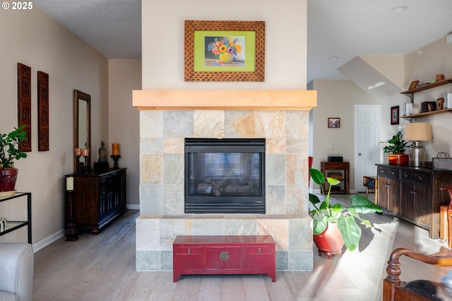 living room with a textured ceiling, light wood-type flooring, and a fireplace