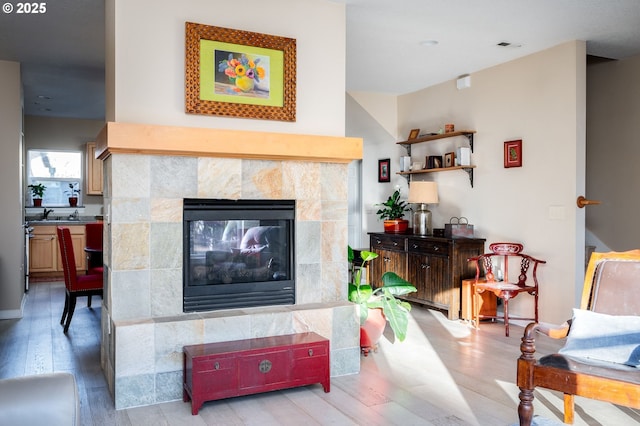 living room with light hardwood / wood-style flooring and a tile fireplace