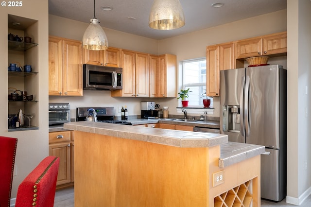 kitchen featuring stainless steel appliances, light brown cabinetry, hanging light fixtures, and sink