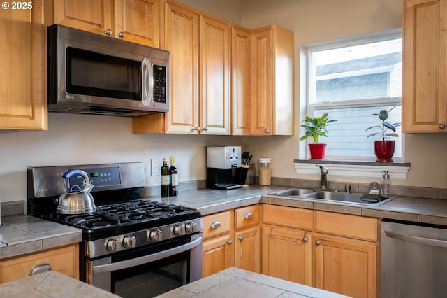 kitchen with stainless steel appliances, tile counters, and sink