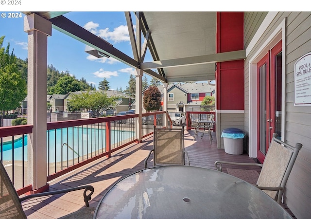 wooden deck with a fenced in pool and a patio